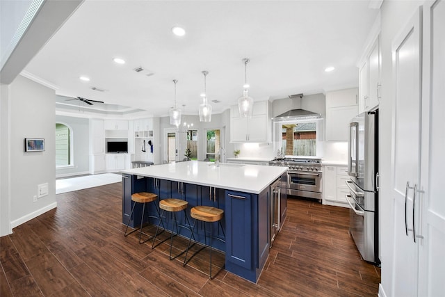 kitchen with a center island with sink, white cabinets, decorative light fixtures, stainless steel appliances, and light countertops