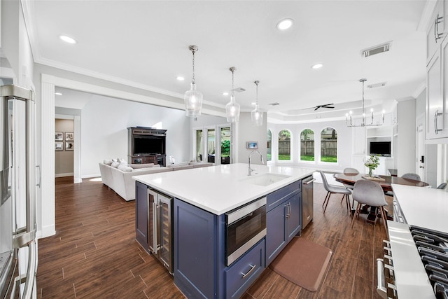 kitchen with sink, blue cabinetry, appliances with stainless steel finishes, white cabinets, and a center island with sink