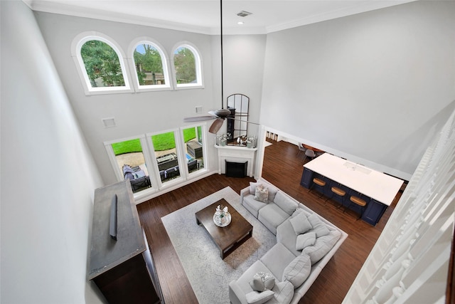 living room featuring a fireplace, visible vents, dark wood-style flooring, and ornamental molding