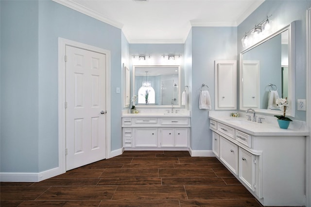 bathroom featuring a sink, two vanities, wood finished floors, baseboards, and ornamental molding