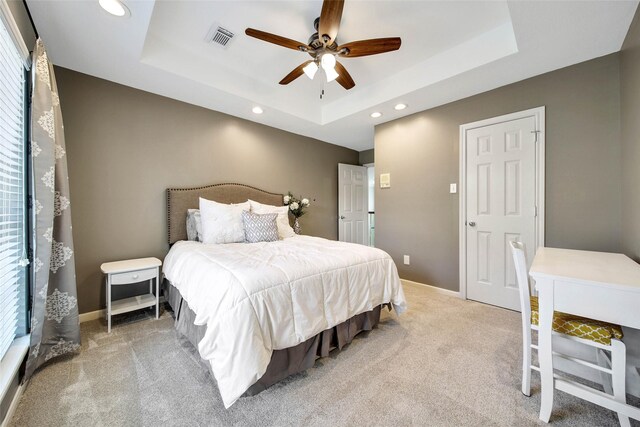 carpeted bedroom with a tray ceiling and ceiling fan