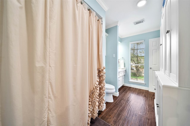 bathroom featuring visible vents, ornamental molding, vanity, wood finished floors, and baseboards