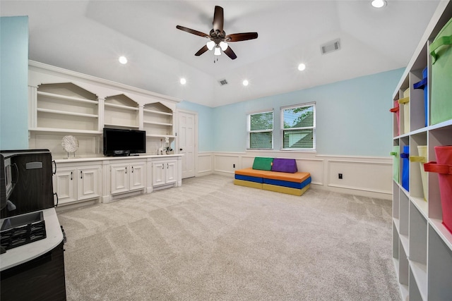 game room with lofted ceiling, a wainscoted wall, light carpet, and visible vents