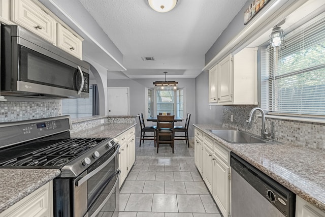 kitchen with tasteful backsplash, pendant lighting, appliances with stainless steel finishes, and sink