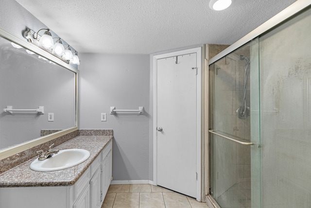 bathroom with walk in shower, tile patterned flooring, vanity, and a textured ceiling