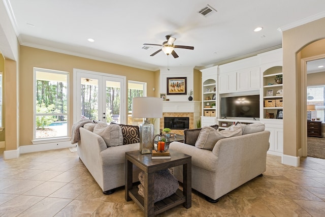 living room with a fireplace, ceiling fan, a healthy amount of sunlight, and crown molding