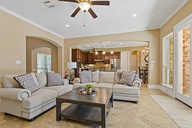 living room with ceiling fan with notable chandelier and ornamental molding