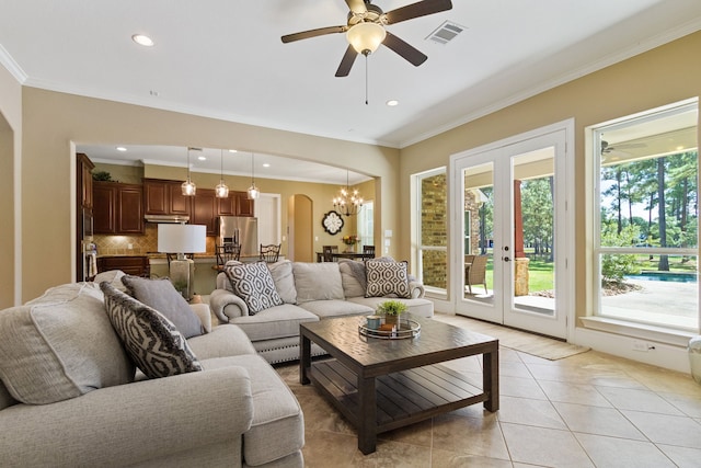 tiled living room with ceiling fan with notable chandelier, ornamental molding, and plenty of natural light