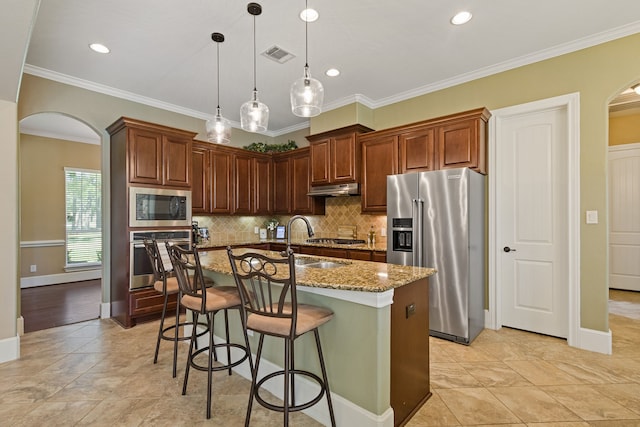 kitchen with stainless steel appliances, a center island with sink, light stone counters, sink, and ornamental molding