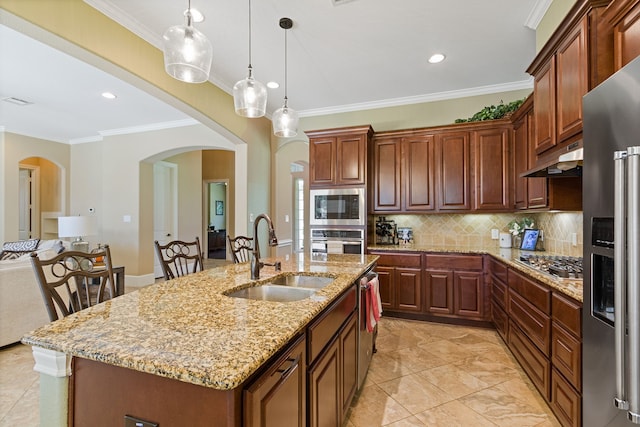 kitchen with sink, appliances with stainless steel finishes, light stone countertops, an island with sink, and crown molding