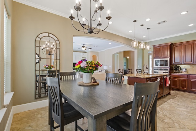 dining room featuring ceiling fan with notable chandelier, sink, and ornamental molding