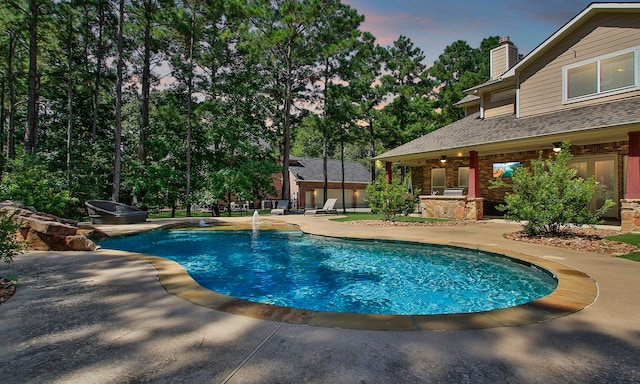 pool at dusk featuring a patio area