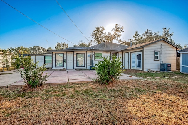 rear view of house featuring central AC unit, a patio area, and a lawn