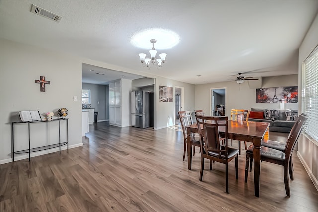 dining area featuring a textured ceiling, hardwood / wood-style floors, and ceiling fan with notable chandelier