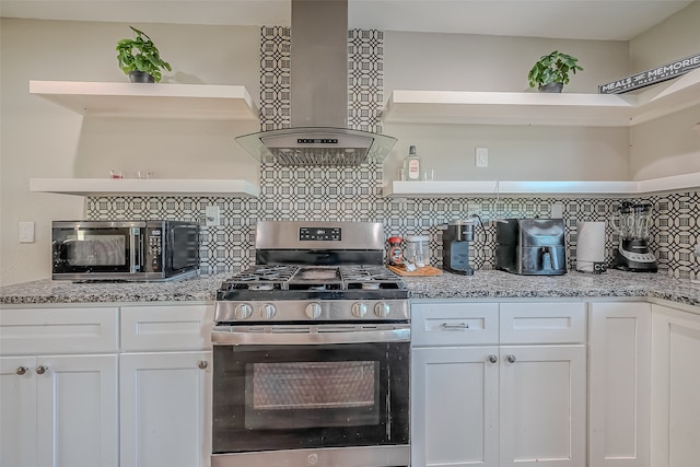 kitchen with light stone countertops, wall chimney range hood, tasteful backsplash, white cabinets, and stainless steel range with gas stovetop