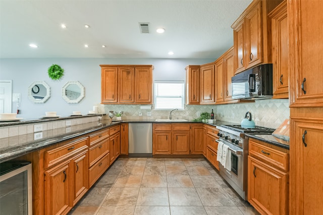 kitchen featuring appliances with stainless steel finishes, wine cooler, dark stone countertops, and sink