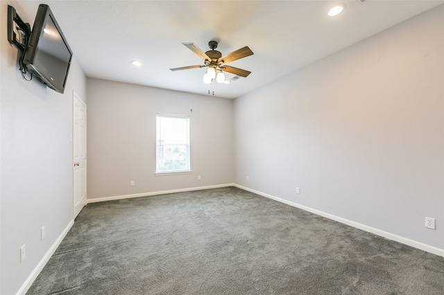 spare room with ceiling fan and dark colored carpet