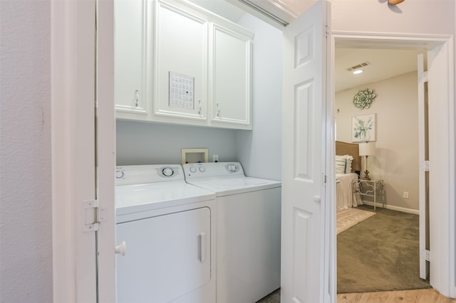 washroom with washer and clothes dryer, light colored carpet, and cabinets