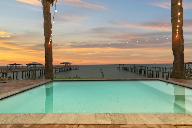 pool at dusk featuring a water view