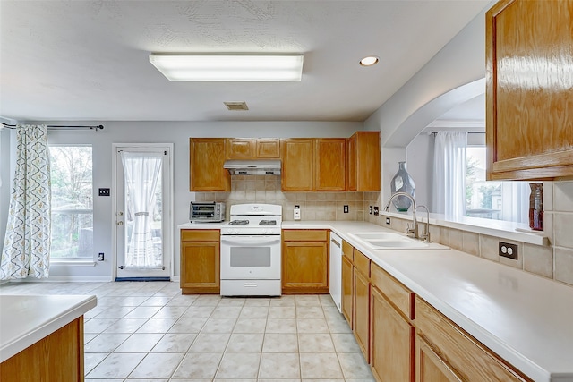 kitchen with decorative backsplash, white appliances, sink, and light tile patterned floors