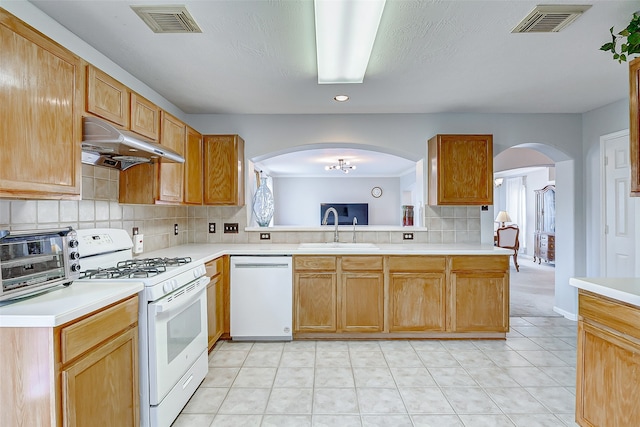 kitchen featuring kitchen peninsula, sink, light tile patterned flooring, backsplash, and white appliances