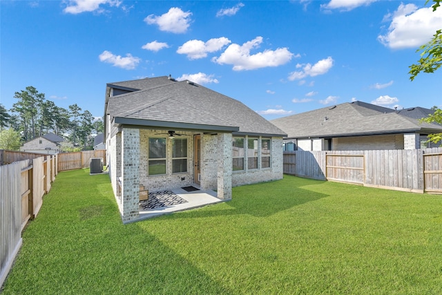 rear view of property with central air condition unit, a patio area, a yard, and ceiling fan