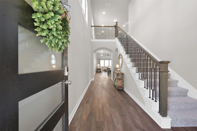 foyer entrance with a towering ceiling and dark hardwood / wood-style floors