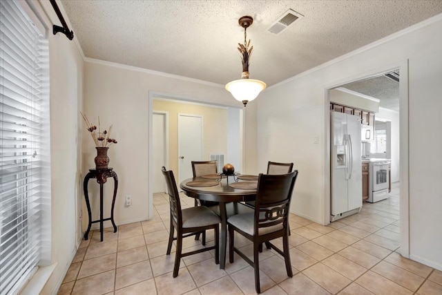 tiled dining area with a healthy amount of sunlight, crown molding, and a textured ceiling