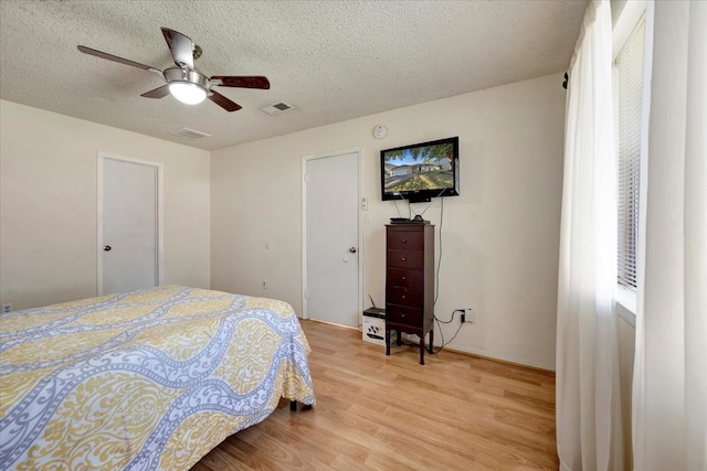 bedroom with a textured ceiling, light hardwood / wood-style floors, and ceiling fan