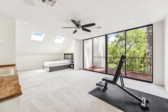 carpeted bedroom featuring ceiling fan, access to exterior, and lofted ceiling with skylight