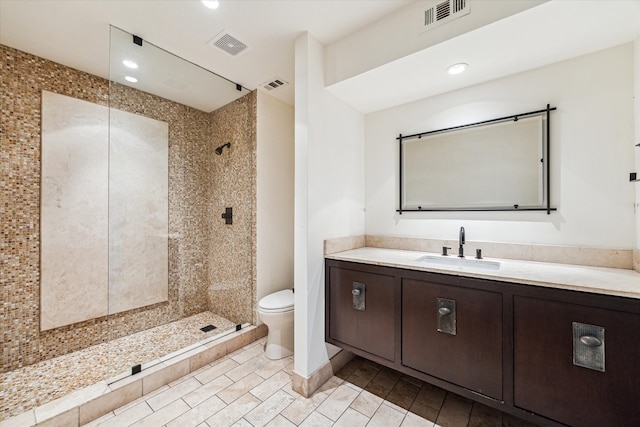 bathroom with toilet, vanity, and a tile shower