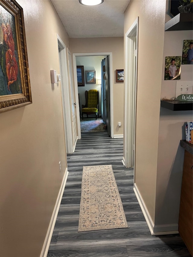 hallway with a textured ceiling and dark hardwood / wood-style floors