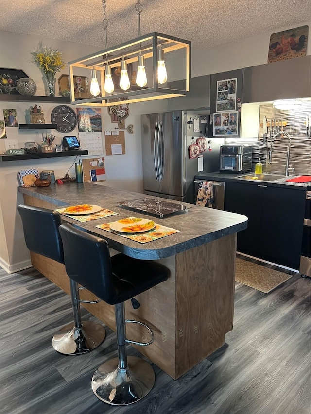 kitchen with appliances with stainless steel finishes, a textured ceiling, a kitchen breakfast bar, and hanging light fixtures