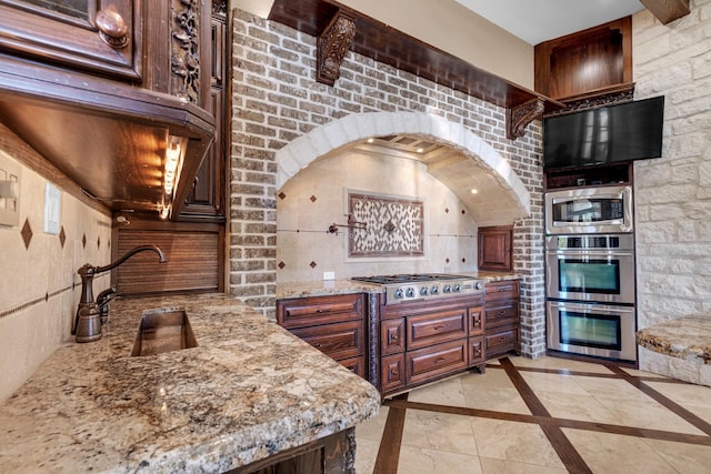 4 Steven Luke Ln, Friendswood, TX 77546 - kitchen featuring stainless steel appliances, light stone counters, arched walkways, and inlaid floor details