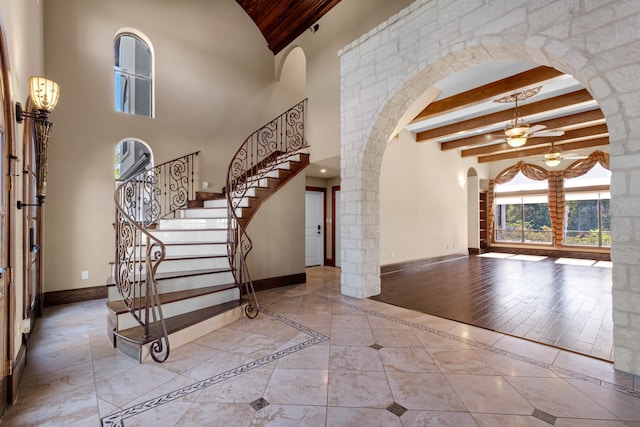 entryway featuring light hardwood / wood-style flooring, a towering ceiling, ceiling fan, and beam ceiling