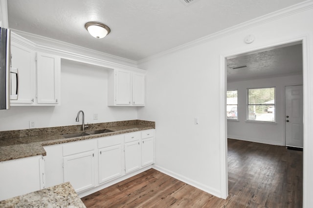 kitchen featuring dark wood-type flooring, white cabinetry, sink, and dark stone counters