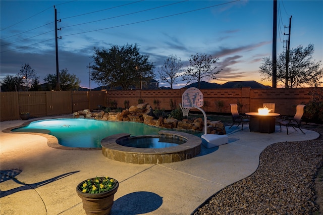 pool at dusk with a patio, an outdoor fire pit, and an in ground hot tub