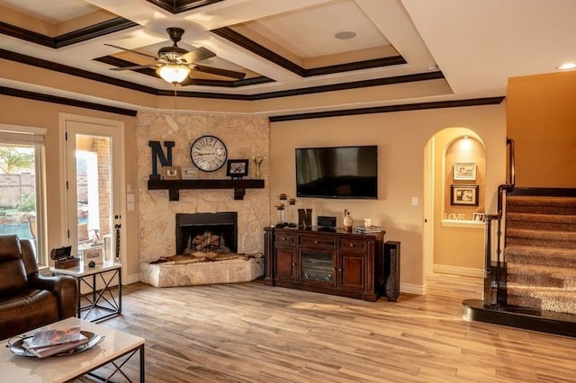 living room featuring a fireplace, ceiling fan, light wood-type flooring, and coffered ceiling