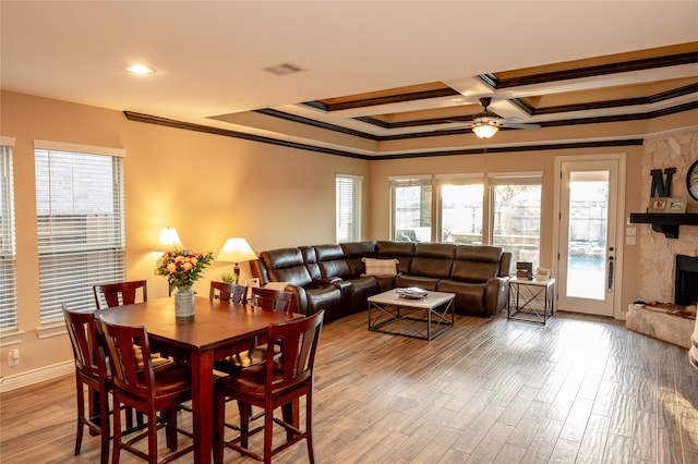 dining room with a fireplace, ceiling fan, light wood-type flooring, and ornamental molding