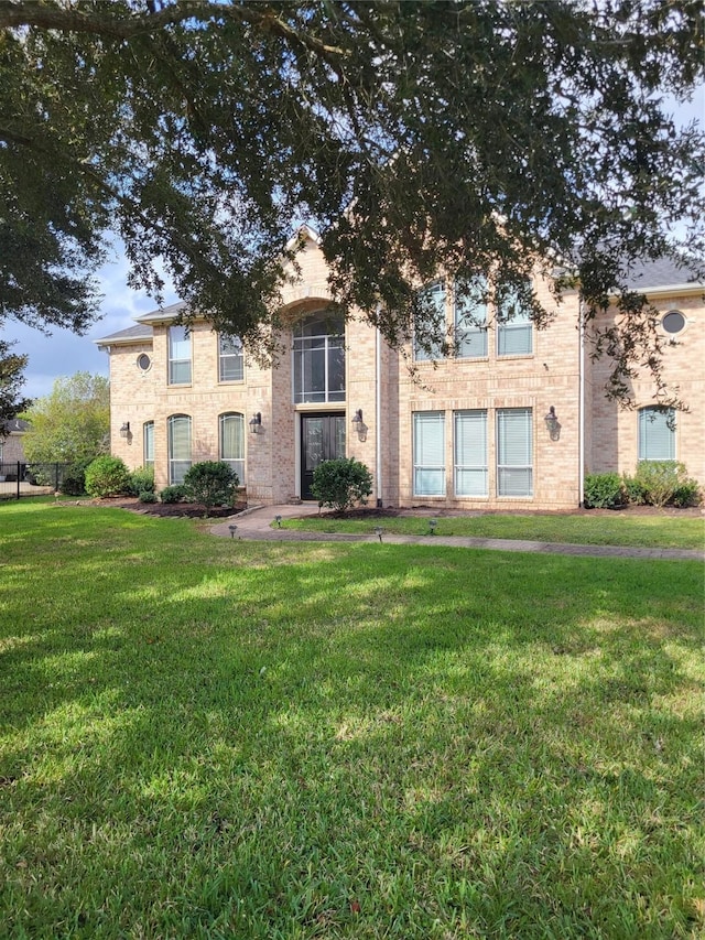 view of front facade featuring brick siding and a front yard