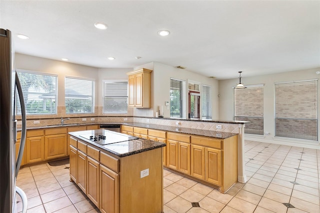 kitchen with stainless steel appliances, a healthy amount of sunlight, a sink, a kitchen island, and a peninsula