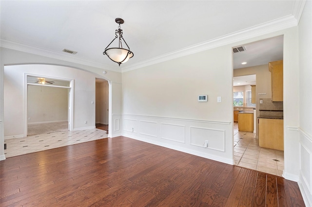 unfurnished dining area featuring ceiling fan, light wood-type flooring, and crown molding