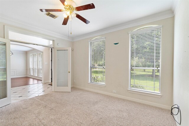 spare room with ceiling fan, crown molding, light carpet, and french doors