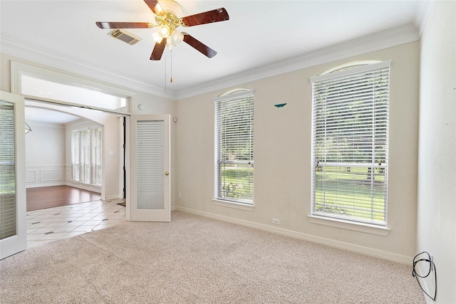 tiled spare room featuring carpet floors, a healthy amount of sunlight, visible vents, and crown molding