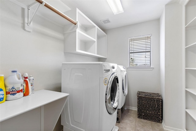 washroom with light tile patterned floors, washing machine and dryer, laundry area, visible vents, and baseboards