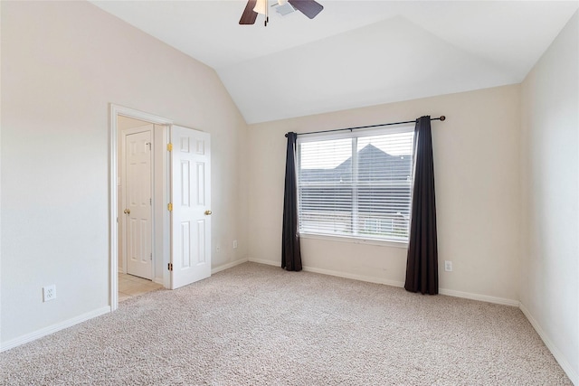 carpeted spare room with lofted ceiling, a ceiling fan, and baseboards