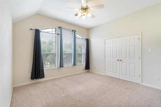 unfurnished bedroom with a closet, light colored carpet, ceiling fan, and lofted ceiling