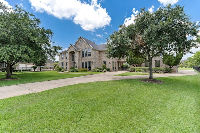 french provincial home featuring concrete driveway, a front lawn, and brick siding