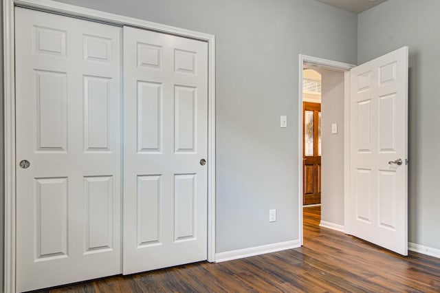 unfurnished bedroom with dark hardwood / wood-style flooring and a closet