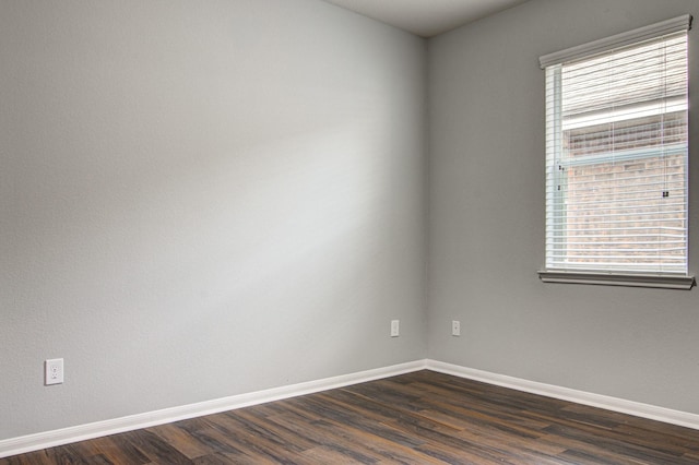 empty room featuring plenty of natural light and dark wood-type flooring